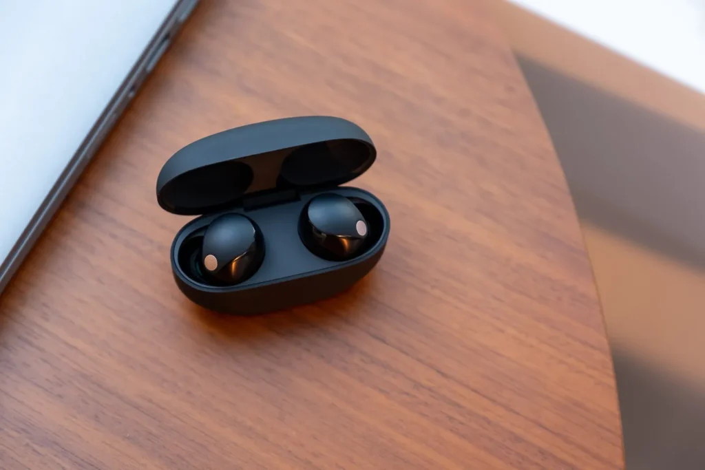 Sony WF-1000XM5 noise-canceling in-ear headphones on a wooden table.