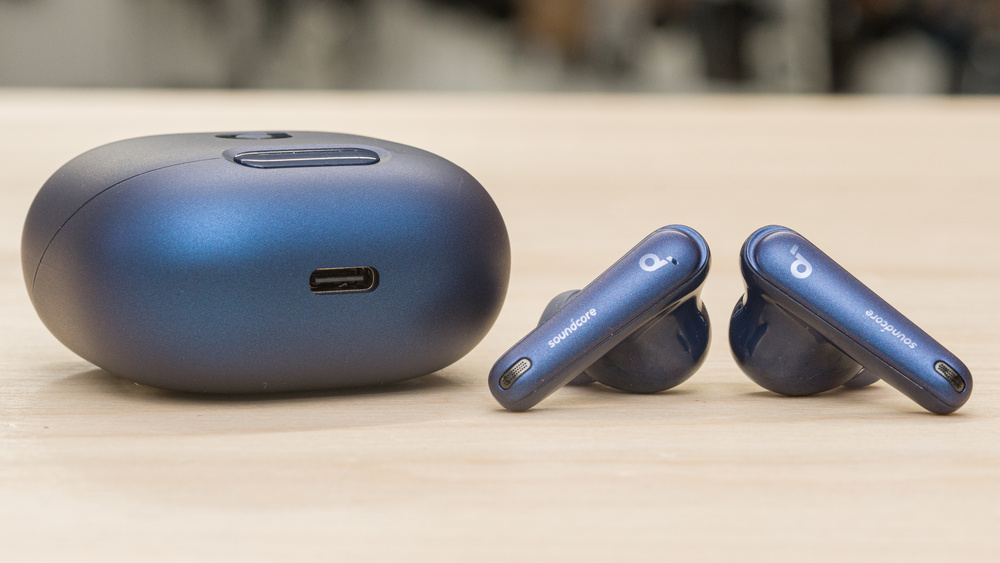 Anker Soundcore Liberty 4 earbuds displayed on a wooden table, showcasing their stylish design and charging case.